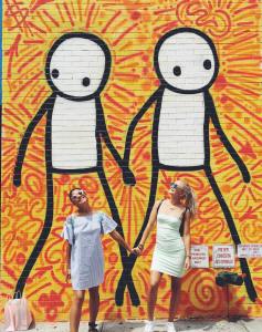 2 girls standing beside orange wall